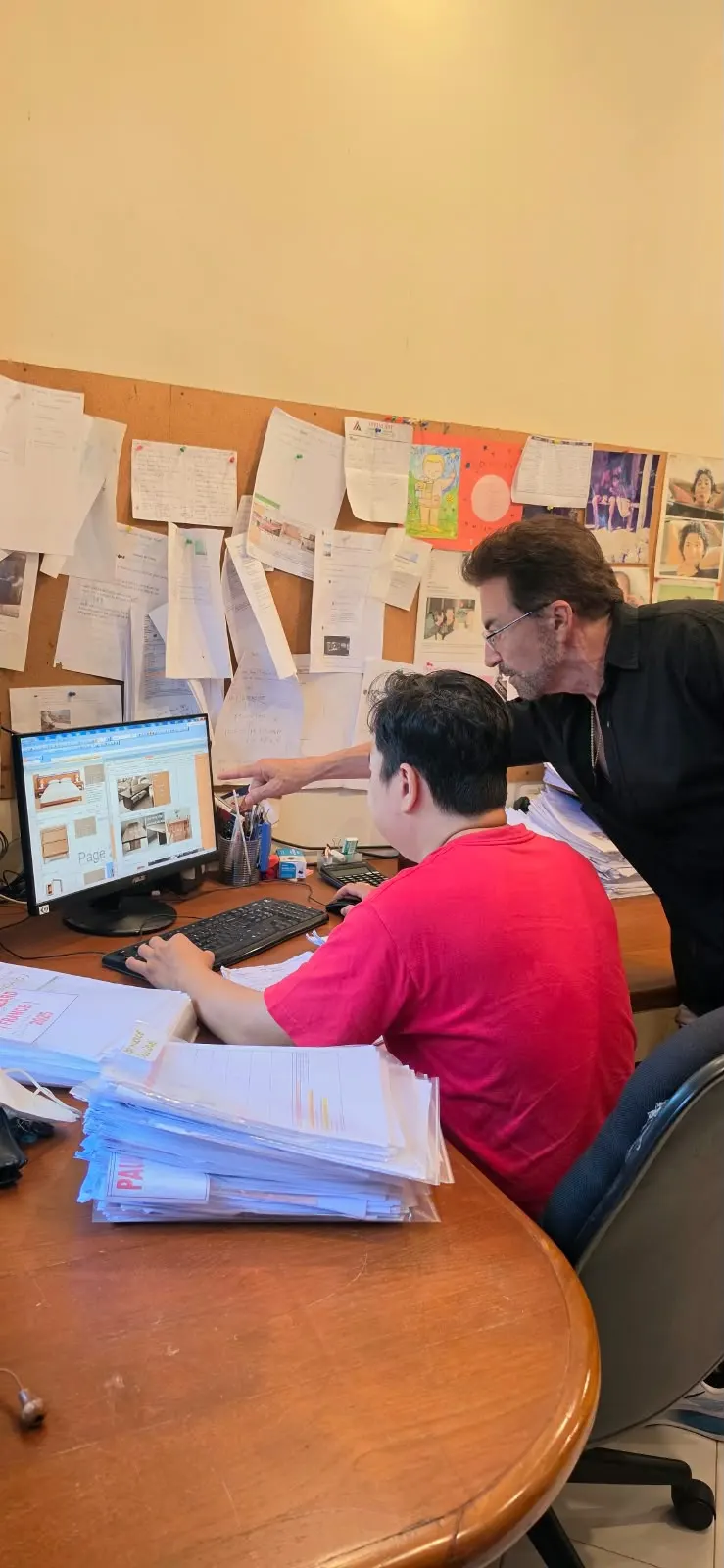 Alain au bureau à Bali, sélectionnant des meubles à l'écran avec un collaborateur
