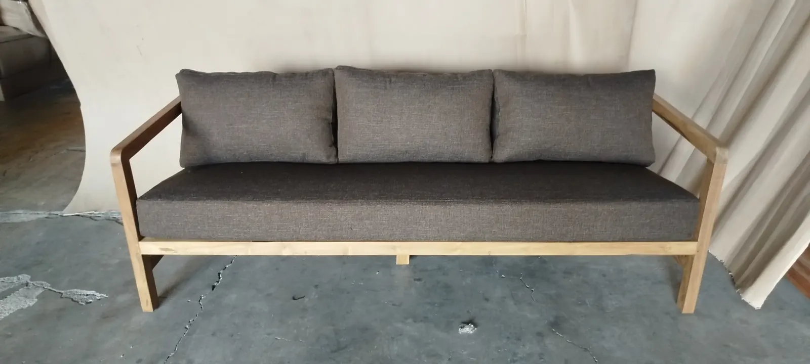Canapé en teck clair, coussins gris anthracite